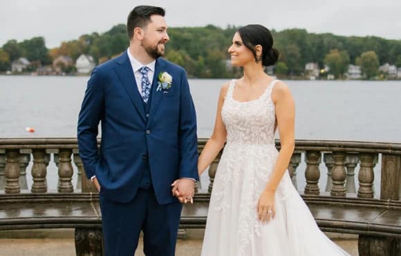 Jacob Stern in his custom wedding suit holding hands with his new bride near the waterfront