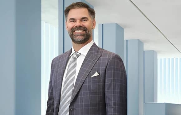 Brian Casey in a custom plaid blazer with a white shirt, and grey/white striped tie