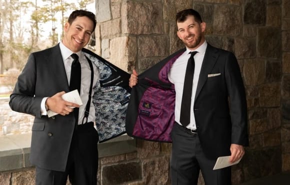 two groomsmen showing their custom suit lining and "Roaring Fashions" tag